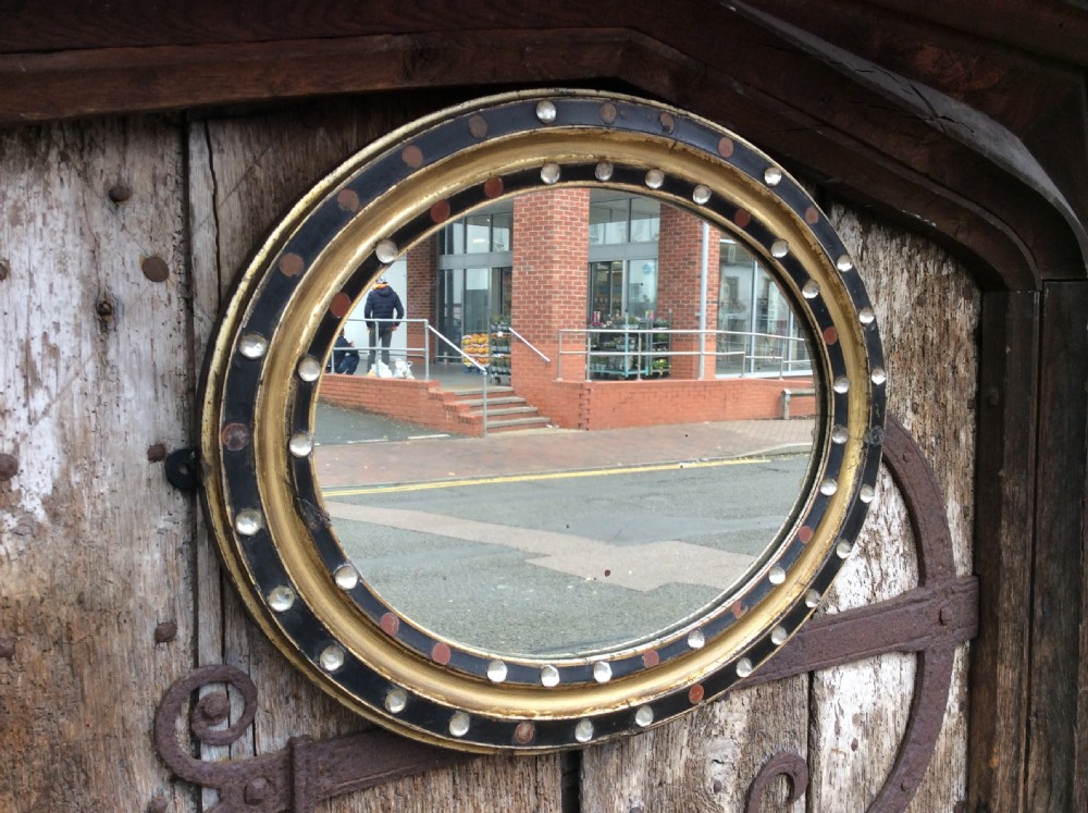 a 19thc oval irish mirror with ebonised gilded frame